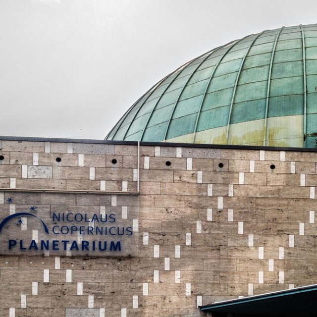 La façade du planétarium Nicolas Copernic à Nuremberg avec un dôme en verre moderne et une enseigne affichant son nom.
