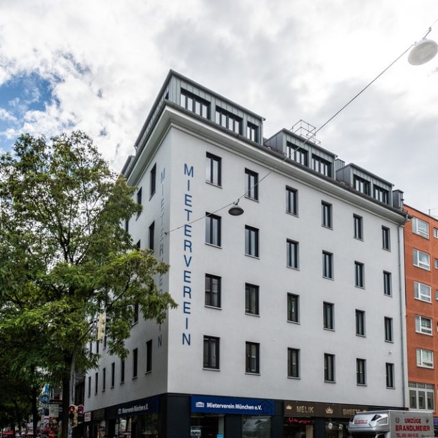 Narożna kamienica przy Sonnenstraße 10 w Monachium, gdzie Adam Chmielowski dzielił pracownię z Maksymilianem Gierymskim. Budynek ma nowoczesną fasadę z dużymi oknami i napisem 'Mieterverein'.