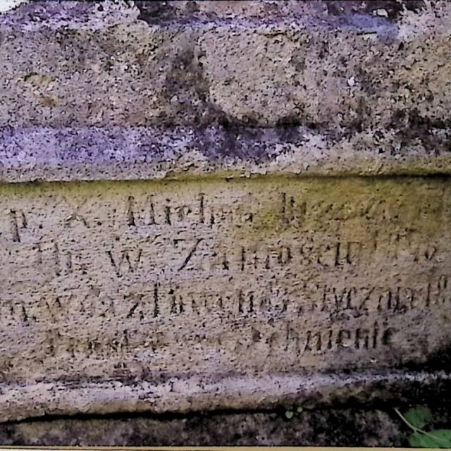 Gravestone of priest Michał N.N. with a cross on a two-tier pedestal. The first tier has an engraved inscription, and the second tier features a relief of a chalice with a host.