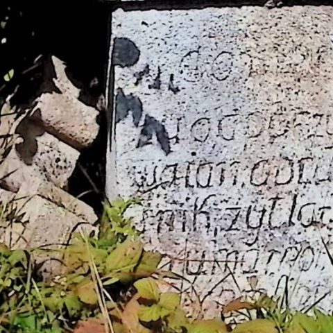 Надгробок Яна Обрушніка з поламаним хрестом поруч. Хрест має трилопатеві кінці та вирізьблений жолобками. П'єдестал переходить у чотирисхилий дах з написом спереду.