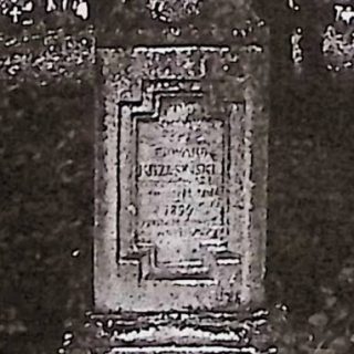 Gravestone of Edward Krzesiński with a cross on a pedestal. The cross is beveled and adorned with floral wreaths. The pedestal narrows upwards with a rectangular plaque featuring an inscription.