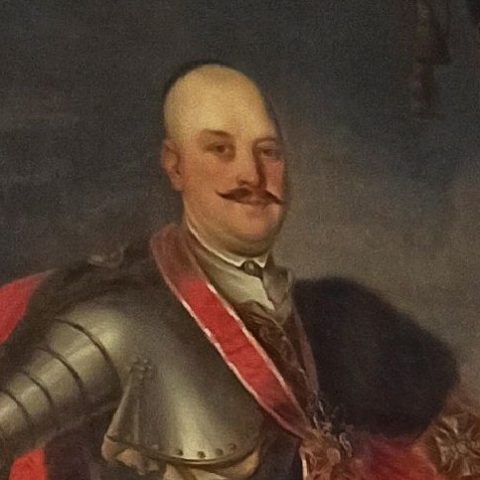 Portrait du comte Adam Józef Mniszech en armure avec une écharpe rouge et des médailles, dont l'Ordre de l'Aigle Blanc, sur un fond sombre.