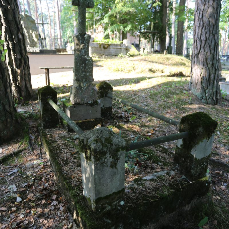 Pierre tombale d'Antonina Płatkowska avec une croix en granit gris sur une base en granit rose, ressemblant à un tronc d'arbre. La tombe est entourée d'une clôture en béton avec des barres de fer.