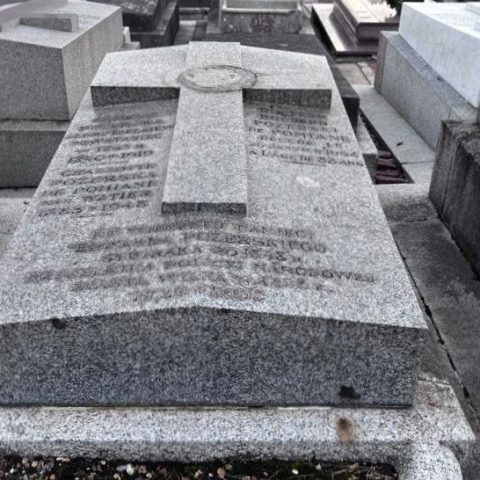Edward Pożerski’s gravestone at the cemetery in Montmorency. The stone is grey, featuring a raised cross and an engraved inscription, and is surrounded by other graves.