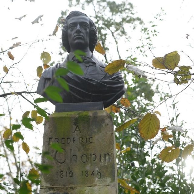 Bust of Frédéric Chopin on a stone pedestal with engraved text 'A Frédéric Chopin 1810-1849', surrounded by autumn leaves in the Luxembourg Gardens, Paris.