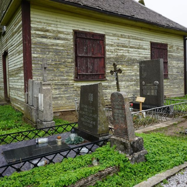 Grób Edwarda Pawłowskiego obok kaplicy, z krzyżem i inskrypcją o tragicznej śmierci w 1944 roku w wieku 24 lat. Otoczony innymi grobami i zielenią.