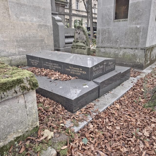 Gravestone of the Doriol and Guyénot families and Luiza Ledóchowska. The rectangular stone features a cross and inscriptions in columns, surrounded by fallen leaves.