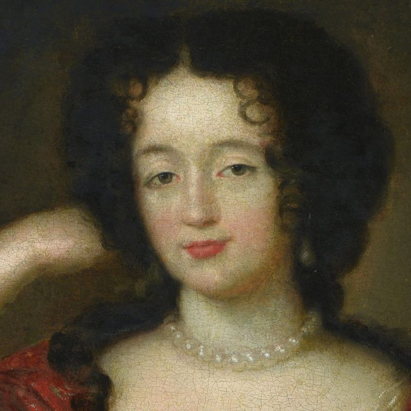 A portrait of a woman with curly dark hair, wearing a pearl necklace and a red outfit, against a dark background.