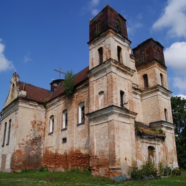 L'église Saint-Michel-Archange à Tartakiv, une structure en brique avec deux tours et un toit rouge, montre des signes d'usure et de végétation sur sa façade.