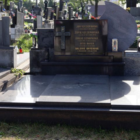 Tombe de la famille Szczepański avec une pierre tombale en trois parties. La partie centrale est plus large et plus haute, avec une inscription gravée et une croix en relief. La stèle repose sur une base à deux niveaux.