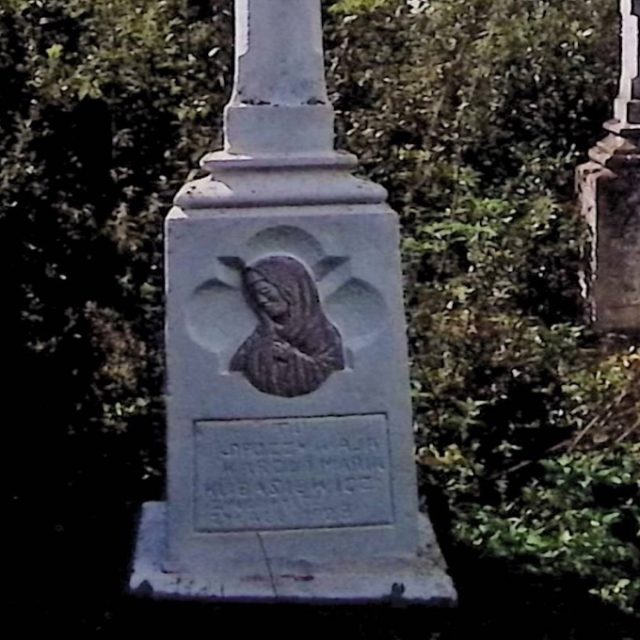 Pierre tombale de Karol et Maria Kubasiewicz avec une croix sur un piédestal. Le devant présente un bas-relief de la Vierge Marie dans un panneau quadrilobé, avec une plaque inscrite en dessous.