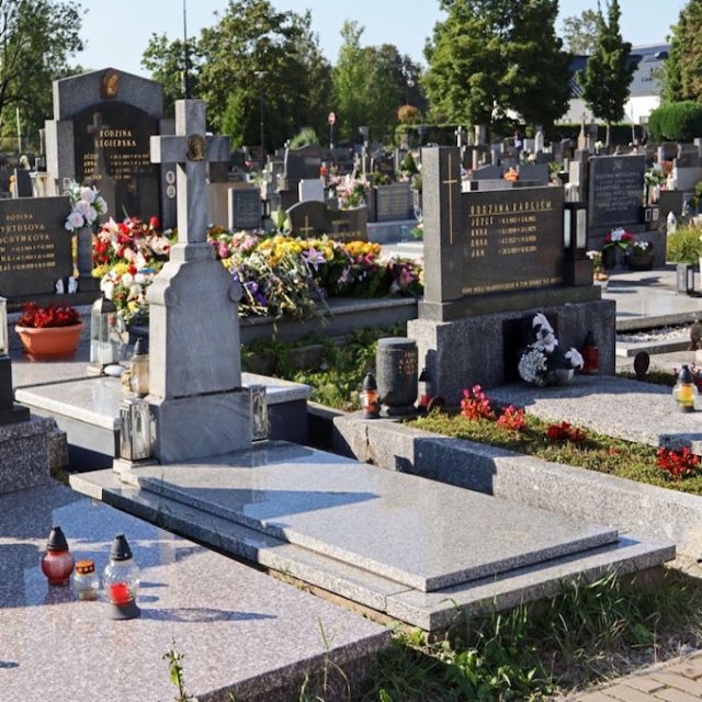 Надгробок Адама і Павла Бойків з хрестом на двоступінчастому постаменті. Христос у терновому вінці на хресті. Напис спереду. На задньому плані кладовище з іншими могилами.