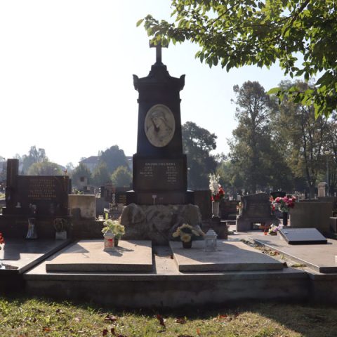 Grób rodziny Pieczko z krzyżem na czterostopniowym cokole. Na najwyższym stopniu marmurowe popiersie Chrystusa w koronie cierniowej. Grób otoczony innymi nagrobkami i drzewami.