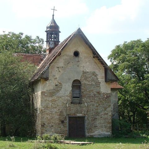 Façade de l'église de la Nativité de la Bienheureuse Vierge Marie à Kobyłowłoki, Ukraine. La structure en pierre présente un pignon triangulaire, une fenêtre ronde et un clocher avec un dôme et une croix.
