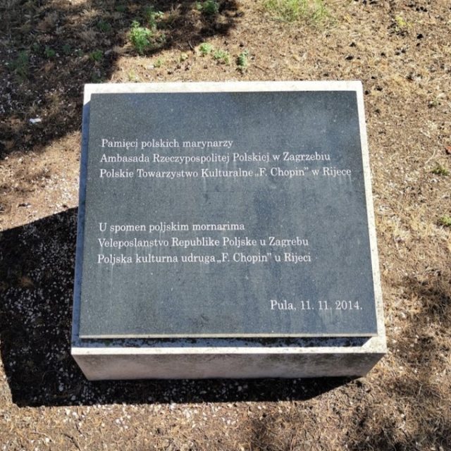 Une plaque commémorative à Pula rendant hommage aux marins polonais, portant une inscription en polonais et en croate, datée du 11 novembre 2014. Entourée d'herbe et de terre.