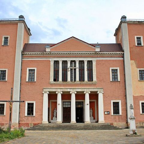 Façade de l'église des Saints Pierre et Paul à Terebovlia, Ukraine, avec une structure à deux étages et un fronton triangulaire, flanquée de deux tours carrées. L'entrée est ornée de colonnes et de statues.