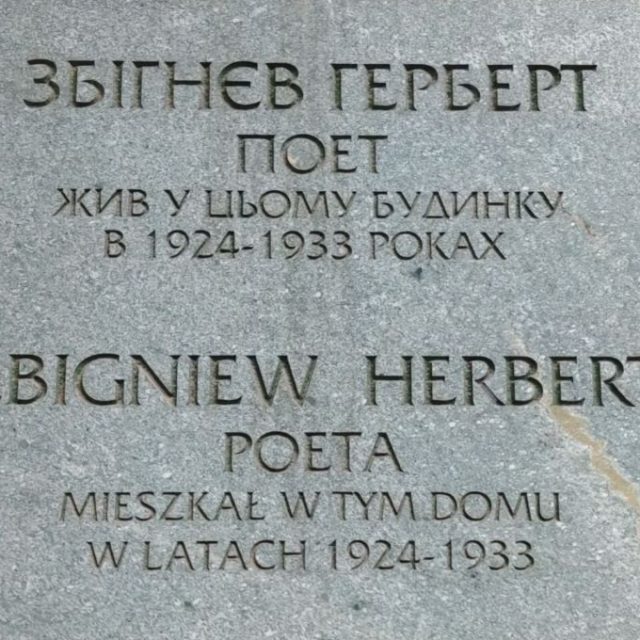 Une plaque commémorative dédiée à Zbigniew Herbert, apposée sur une surface en pierre et comportant des inscriptions en ukrainien et en polonais, indique qu'il a vécu dans cet immeuble de 1924 à 1933.