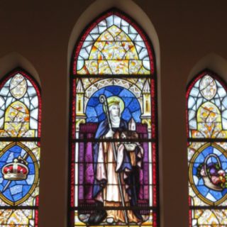 Witraż przedstawiający św. Jadwigę Śląską w kościele Rosenkranskirke, Aakirkeby, Bornholm. Centralny panel ukazuje św. Jadwigę z pastorałem i modelem kościoła, otoczoną motywami dekoracyjnymi.