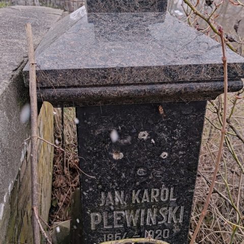 Надгробок Яна Кароля Плевінського, 1867-1920, з написом "Poległ w walce o niepodległość Polski", оточений зарослою рослинністю на цвинтарі Стара Росса.