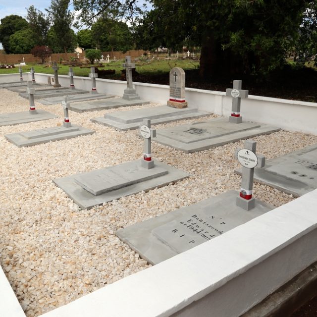 Tombes de réfugiés polonais de l'URSS au cimetière catholique de Kondoa. Douze tombes en ciment avec des croix, entourées d'un muret, sous un grand arbre.