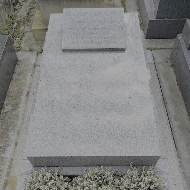 Tombstone of Anatoly and Renée Jakovsky with a high plinth and a stepped, slightly angled slab. Inscriptions on a pulpit-shaped plaque and a porcelain plate resembling an open book.