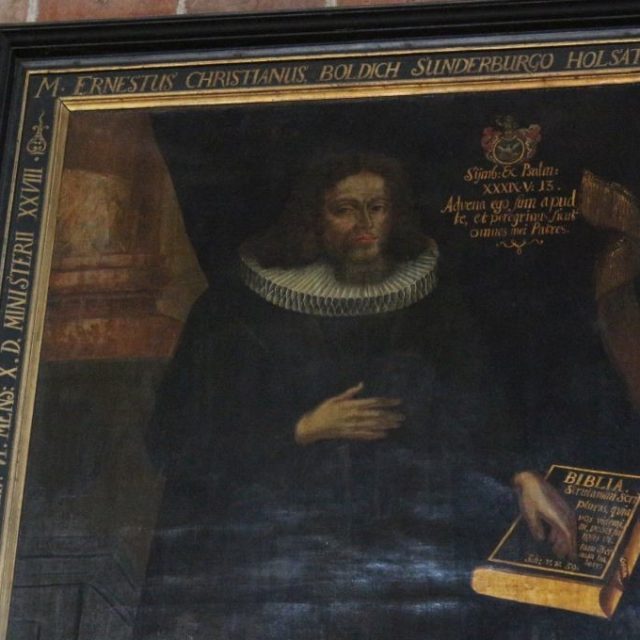 Portrait du pasteur Ernest Ch. Boldich avec orifice, tenant un livre portant l'inscription "Bible". Le cadre contient des inscriptions en latin et en allemand. Le fond est sombre et le tableau porte des traces d'usure.
