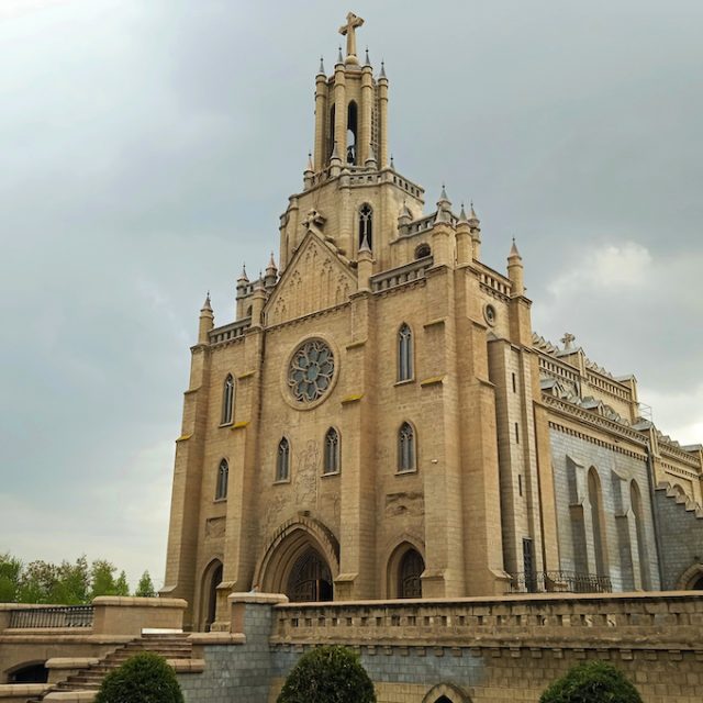 Photographie de l église catholique du Sacré Coeur de Jésus à Tachkent avec une haute tour surmontée d une croix et une façade en pierre avec une rosace