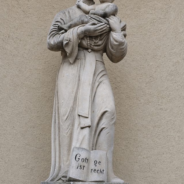 Statue en pierre de saint Gaétan sur la façade de l église à Suceava. Le saint se tient en robe et porte l Enfant Jésus sur le bras gauche. Un livre ouvert à ses pieds porte Gott ge ist recht. Le socle porte S Kajetan.