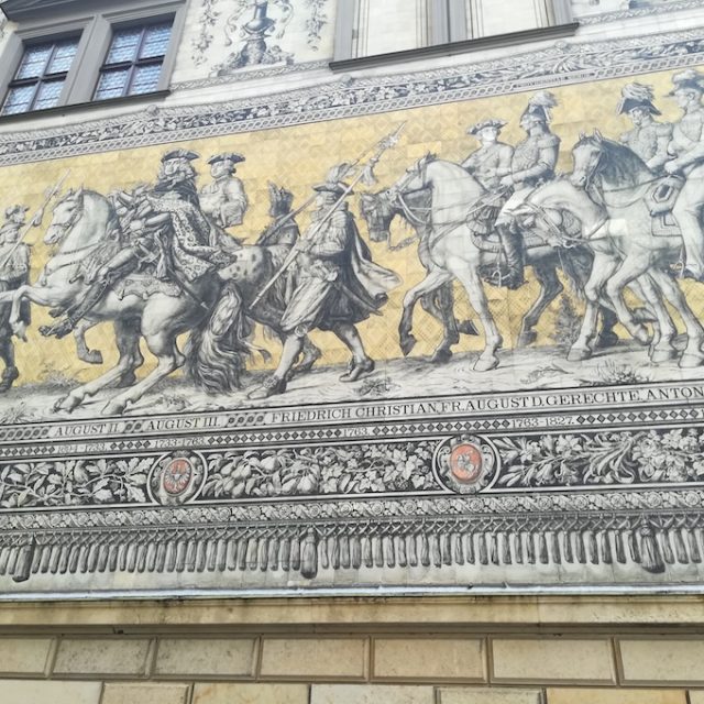 Porcelain mural of the Procession of Princes in Dresden with riders, walking figures and a row of coats of arms below.